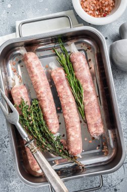 Mutfak tepsisinde çiğ sosisli domuz eti sosisi. Gri arka plan. Üst görünüm