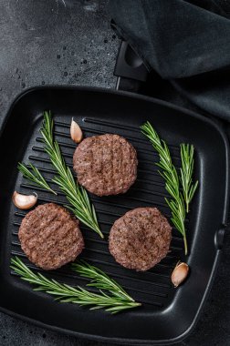 Izgara burgerli köfte ve ızgara tavada baharat. Siyah arka plan. Üst görünüm