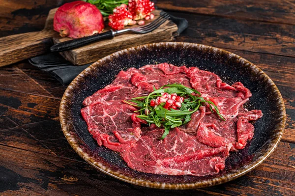 Carpaccio marbled beef meat with arugula and pomegranate seeds. Wooden background. Top view — Stock Photo, Image