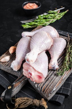 Taze çiğ tavuk budu bacakları tahta kesme tahtasının üzerinde. Siyah arka plan. Üst görünüm