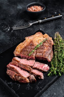 Kızarmış bbq Chuck Roll bifteği ve otlar. Siyah arka plan. Üst görünüm