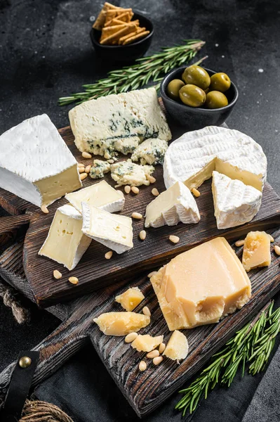 Deliciosa tábua de queijo. Sortimento de queijo, camembert, brie, Gorgonzola, parmesão, azeitonas, nozes e ervas. Fundo preto. Vista superior — Fotografia de Stock