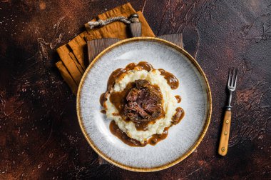 Kırmızı şarap soslu ve patates püresiyle yavaş pişmiş sığır eti yanakları. Karanlık arka plan. Üst görünüm