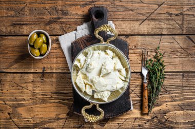 Zeytin ve biberiyeli bir tavada keçi ve koyun peyniri. Ahşap arka plan. Üst görünüm