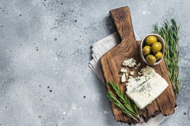 Tahtada zeytin ve biberiyeli Danimarka peyniri. Gri arka plan. Üst Manzara. Boşluğu kopyala