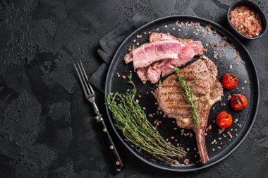 Pembe tuzlu bir tabakta barbekü dilimlenmiş Tomahawk bifteği. Siyah arka plan. Üst Manzara. Boşluğu kopyala