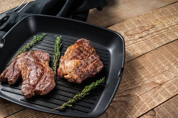 Grilled Chuck eye Roll beef steaks with herbs on grill skillet. Wooden background. Top view. Copy space — Stock Photo, Image