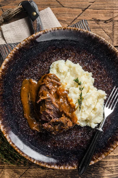 Beef cheeks stewed in red wine sauce with mashed potatoes. Wooden background. Top view