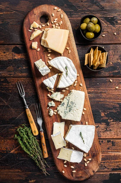Prato de queijo com camembert, brie, Gorgonzola, parmesão, azeitonas, nozes e bolachas. Fundo de madeira. Vista superior — Fotografia de Stock