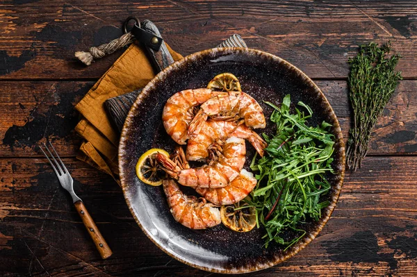 Spicy garlic Giant shrimps prawns in plate with salad. Wooden background. Top view — Fotografia de Stock