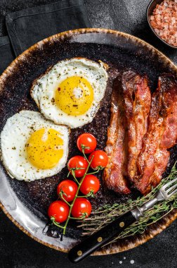 Yağda yumurta ve jambonlu kahvaltı tabakta otlar. Siyah arka plan. Üst görünüm