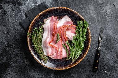 Çiğ domuz pastırması otlarla pişirilmeye hazır. Siyah arka plan. Üst görünüm