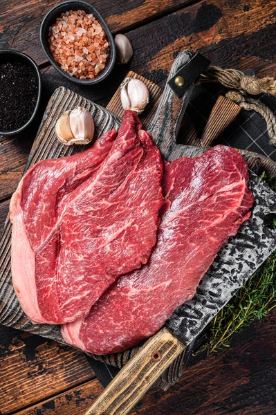 Rauw vlees met kruiden op de snijplank van de slager. Houten achtergrond. Bovenaanzicht — Stockfoto
