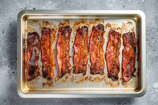 Strips av stekt bacon i bakform. Grå bakgrund. Ovanifrån — Stockfoto
