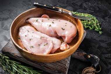 Dilimlenmiş çiğ tavuk göğsü fileto, tavuklu biftekler tabakta. Siyah arka plan. Üst görünüm