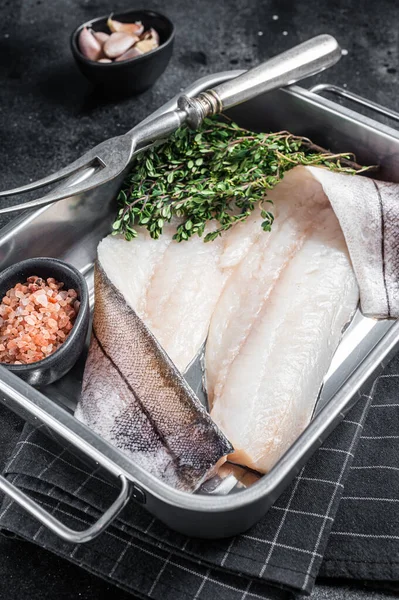 Raw haddock fish fillets, whitefish meat in kitchen tray with thyme. Black background. Top view — Stockfoto
