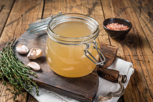 Bone broth for chicken soup in a glass jar. Wooden background. Top view — Fotografia de Stock