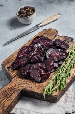 Tahta tahtada kurutulmuş sosis ve şifalı otlar. Gri arka plan. Üst görünüm