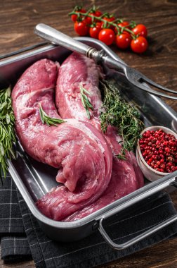 Taze çiğ domuz filetosu, pişirilmemiş fileto mutfak tepsisinde bitkilerle birlikte. Ahşap arka plan. Üst görünüm