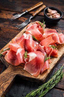 Jamon serrano jambonu dilimleri ya da ahşap tahtada biberiyeli prosciutto crudo parma. Ahşap arka plan. Üst görünüm