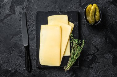 Mermer tahtada pişmemiş taze Raclette İsviçre peyniri dilimleri. Siyah arka plan. Üst görünüm