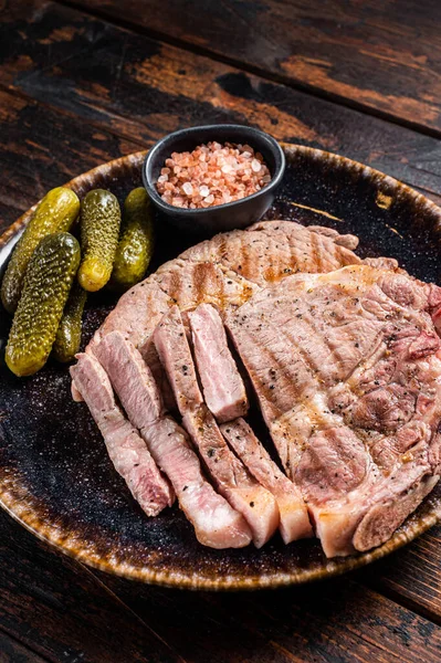 Grillet kjøtt - svinekjøtt fra halsfilet kjøtt i tallerken med syltede agurker. Trebakgrunn. Sett ovenfra – stockfoto