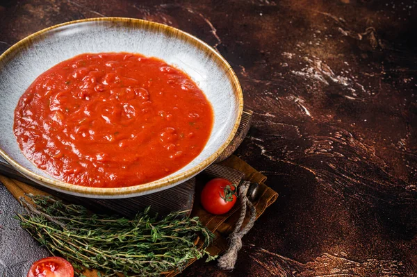 Homemade tomato Passata in rustic plate with herbs. Dark background. Top view. Copy space — Stock Fotó