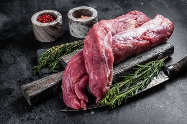 Sığır filetosu çiğ et, ahşap tahtada pişirilmemiş fileto ve bitkiler. Siyah arka plan. Üst görünüm