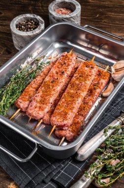 Çiğ Urfa şiş kebabı kasap tepsisinde otlarla. Ahşap arka plan. en üstteki görünüm