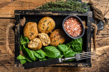 Balık köftesi mi yoksa ıspanaklı ve şifalı otlu balık köftesi mi? Ahşap arka plan. Üst görünüm