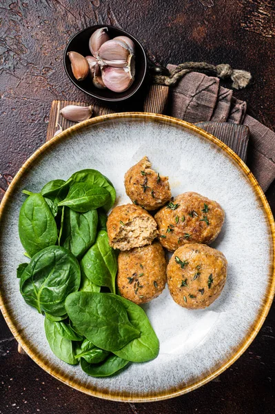 Fish Cakes or Fish balls with tuna and spinach in a plate. Dark background. Top view