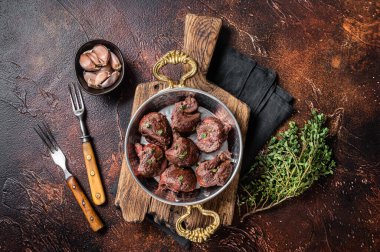 Kızarmış sığır böbreği, tavada sakatat eti ve şifalı otlar. Karanlık arka plan. Üst görünüm