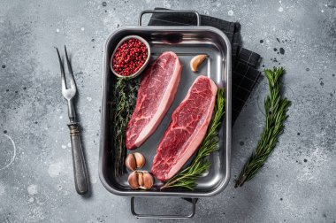 Çiğ sığır filetosu ya da tepside otlu biftek. Gri arka plan. Üst görünüm