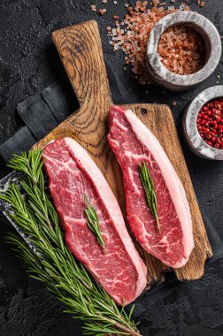 Çiğ sığır etli biftek ya da kasap panosunun üstünde sığır filetosu. Siyah arka plan. Üst görünüm