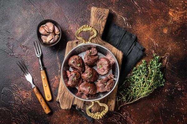Roasted beef kidney, offal meat in skillet with herbs. Dark background. Top view —  Fotos de Stock
