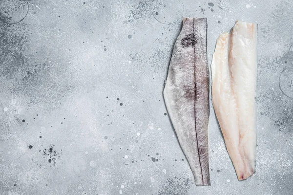 Two raw haddock fish fillets on kitchen table. Gray background. Top view. Copy space — Stockfoto