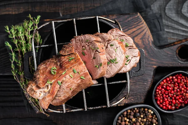 Roast beef on a grill, tenderloin sliced meat with herbs. Black Wooden background. Top view — Stock Photo, Image