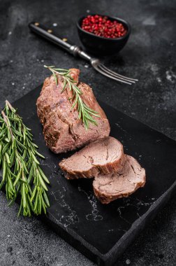 Dilimlenmiş bonfile biftek, mermer tahtada rosto ve biberiye. Siyah arka plan. Üst görünüm