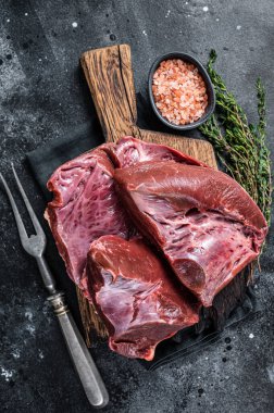 Çiğ sığır eti ya da kasap tahtasındaki dana kalbi. Siyah arka plan. Üst Görünüm