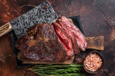 Kızarmış askı ya da kasap tahtasında satırla dilimlenmiş biftek. Karanlık arka plan. Üst Görünüm