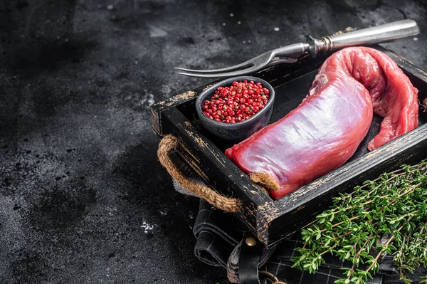 Lombo de carne de vitela cru inteiro em bandeja de madeira. Fundo preto. Vista superior. Espaço de cópia — Fotografia de Stock