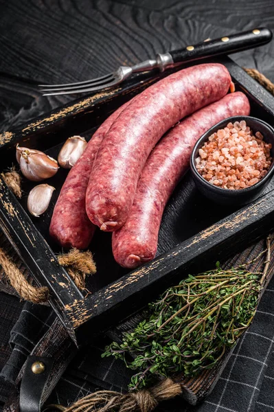 Embutidos crudos Bratwurst, carne fresca en bandeja de madera con tomillo. Fondo de madera. Vista superior —  Fotos de Stock
