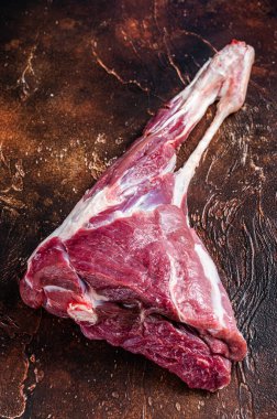 Kemiğin üzerinde bütün çiğ kuzu bacağı eti. Karanlık arka plan. Üst görünüm