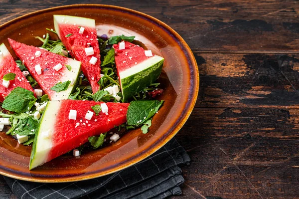 Frisse zomer watermeloen salade met feta kaas, arugula, uien in een rustieke plaat. Donkere achtergrond. Bovenaanzicht. Kopieerruimte — Stockfoto