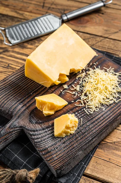 Pezzo di formaggio cheddar grattugiato su una tavola di legno. Sfondo in legno. Vista dall'alto — Foto Stock
