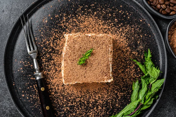 Bolo Tiramisu italiano com cacau e hortelã em um prato. Fundo preto. Vista superior — Fotografia de Stock