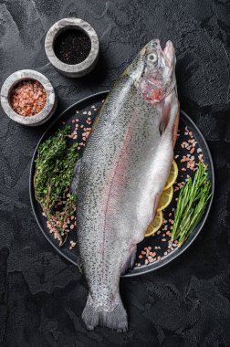 Çiğ deniz alabalığı, taze balık ve şifalı otlar. Siyah arka plan. Üst görünüm