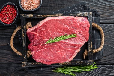 Tahta tepside otlu biftekler için çiğ biftek fileto. Siyah ahşap arka plan. Üst görünüm