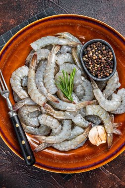 Köy tabağında çiğ, kafasız dev karides karidesi. Karanlık arka plan. Üst görünüm