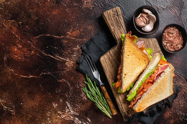 Klassisches BLT-Sandwich mit Speck, Tomate und Salat auf Holzbrett mit Kräutern. Dunkler Hintergrund. Ansicht von oben. Kopierraum — Stockfoto